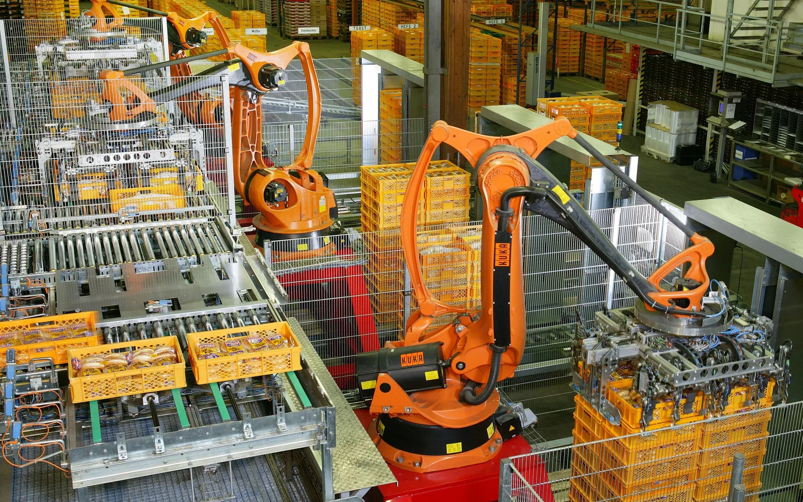 Industrial robotic arms palettizing products in an automated manufacturing facility